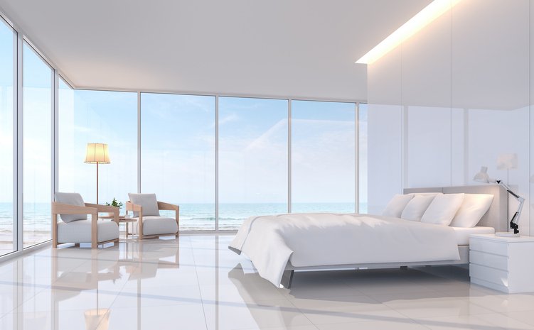 Modern white bedroom with sea view 3d rendering image.There are white tile floor and white glossy wall.Furnished with white furniture.There are large window overlooks to sea view.